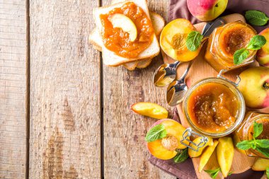 Farklı kavanozlarda ev yapımı şeftali reçeli ve ahşap arka planda taze organik şeftali.