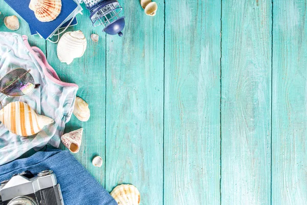 Bright  summer flat-lay background. Old blue wooden background with with summer woman clothes, sun glasses, hat, camera, passports and vacation tickets