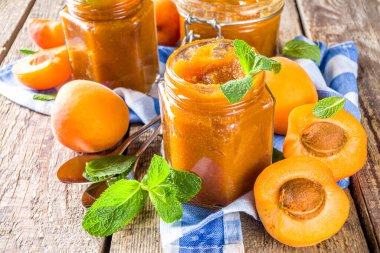 Farklı kavanozlarda ev yapımı kayısı reçeli, ahşap arka planda taze organik kayısılar fotokopi alanı