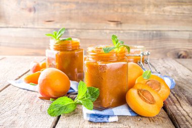 Farklı kavanozlarda ev yapımı kayısı reçeli, ahşap arka planda taze organik kayısılar fotokopi alanı