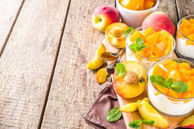 Konserve ve taze şeftalili yoğurt tatlısı, ahşap hışırtılı arka planda. Yaz kahvaltısı meyveli tatlı.