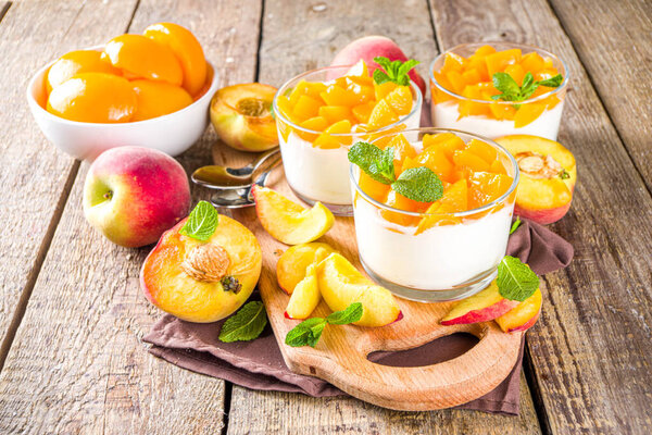 Десерт из творога или йогурта с консервированными и свежими персиками, на деревянном фоне из шелухи. Летний фруктовый десерт
.