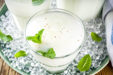 Soğuk Hint içeceği Lassi, buzlu hindistan cevizi Lassi, nane yaprağı, ahşap arka plan kopyalama alanı