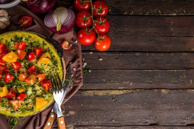 Ev yapımı rustik frittata. Tavada ıspanaklı, peynirli ve domatesli frittata. Sebzeli ahşap arkaplan Kopya alanı