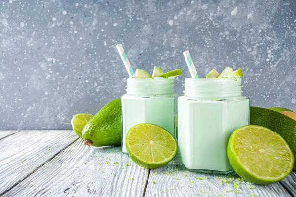 Avocado Milk Shake or Smoothie, Yogurt with Avocado and Lime Juice, with Fresh Avocados and limes on wooden background copy space