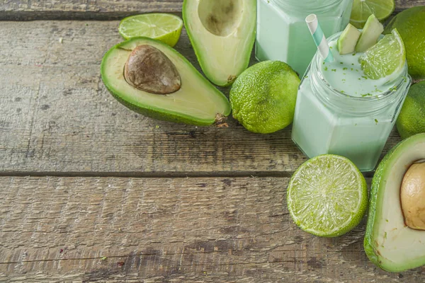 Avocado Milk Shake or Smoothie, Yogurt with Avocado and Lime Juice, with Fresh Avocados and limes on wooden background copy space