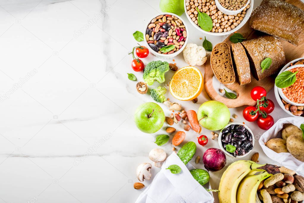 Healthy food. Selection of good carbohydrate sources, high fiber rich food. Low glycemic index diet. Fresh vegetables, fruits, cereals, legumes, nuts, greens. White marble background copy space