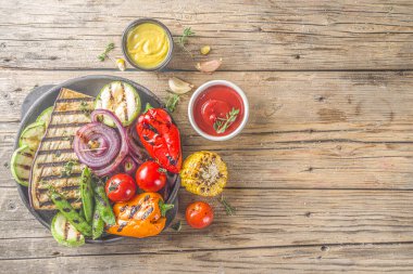 Sıcak sebze salatası. Tabağa farklı ızgara sebzeler koyun. Vejetaryen barbekü pikniği seti, kuşkonmaz, domates, mantar, biber, mısır ve sos.