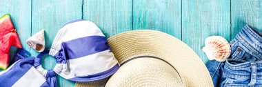 Yaz tatili konsepti. Denizde yaz tatili. Kadın mayosu, şort ve hasır şapka. Mavi ahşap arka planda karpuz dilimleri ve deniz kabukları var. Üst görünüm kopyalama alanı oluştur