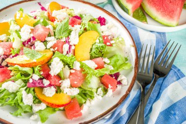 Yaz diyet salatası, marul, karpuz, şeftali ve peynir yaprakları. Açık mavi arkaplan kopyalama boşluğunda