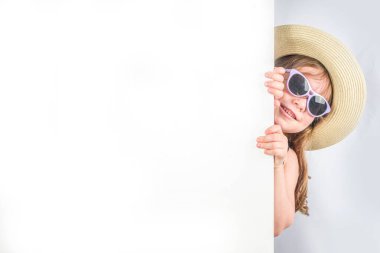 Yaz tatili ve tatil konsepti. Güneş gözlüklü, yaz şapkalı, gülümseyen tatlı bir kız. Tatil afişi için arka plan, model