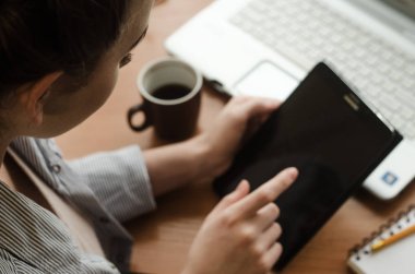 Bir dizüstü bilgisayar oturma ve tutan genç kadın bir elinde bir tablet