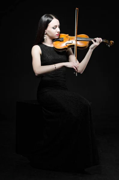 Uma jovem mulher em um vestido preto com um violino — Fotografia de Stock