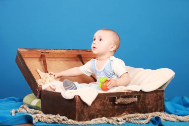 Bir göğüs denizci elbiseli çocuk mavi bir arka plan üzerinde oturur