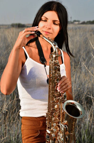 Kobieta dostosowuje stojących saksofon w środku pola — Zdjęcie stockowe