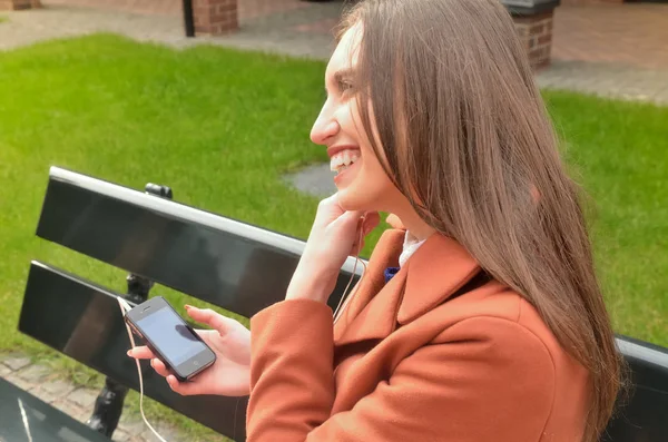 Una Chica Bonita Sentada Banco Sonriendo Escuchando Música Los Auriculares —  Fotos de Stock