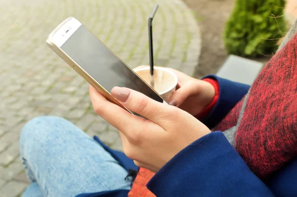 Bir telefon ve bir fincan kahve kadınların elinde. Üzerinde çivi güzel bej cilaya güzel manikür var. Yatay fotoğraf