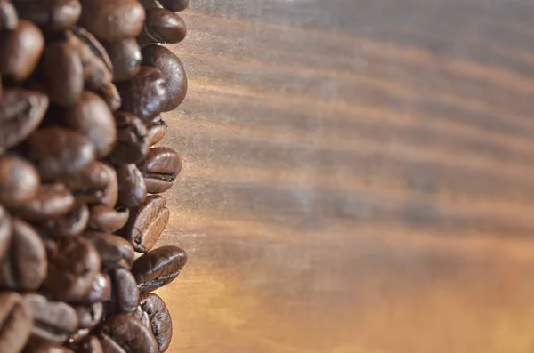 Muchos granos de café se encuentran a la izquierda sobre un fondo de madera . —  Fotos de Stock