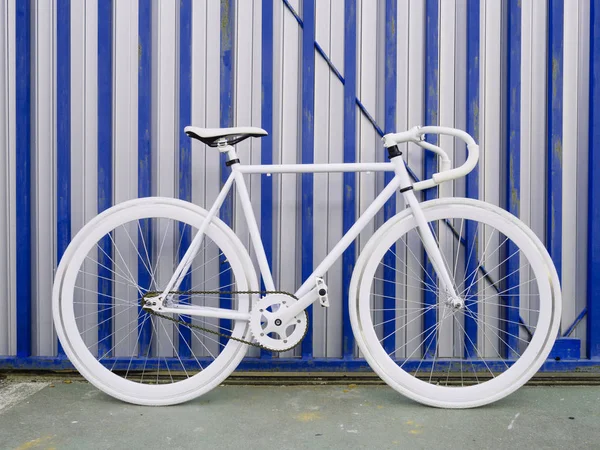 Bicicleta branca de engrenagem fixa da cidade na parede branca e azul . — Fotografia de Stock