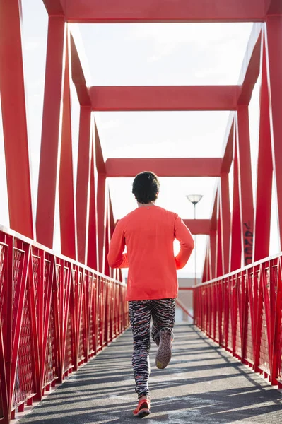 Jovem correndo pela ponte vermelha, de volta — Fotografia de Stock