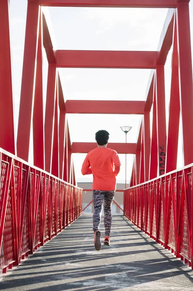 Jovem correndo pela ponte vermelha, de volta — Fotografia de Stock