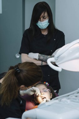 Diş hekimleri çocuk diş bir müdahale sırasında bir hastayla