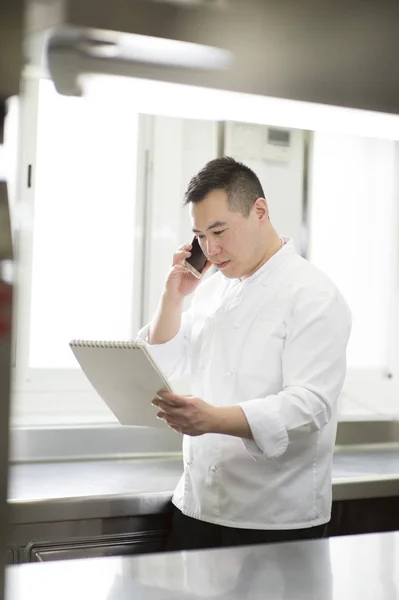 Cozinheiro chinês fala com smartphone e notebook — Fotografia de Stock