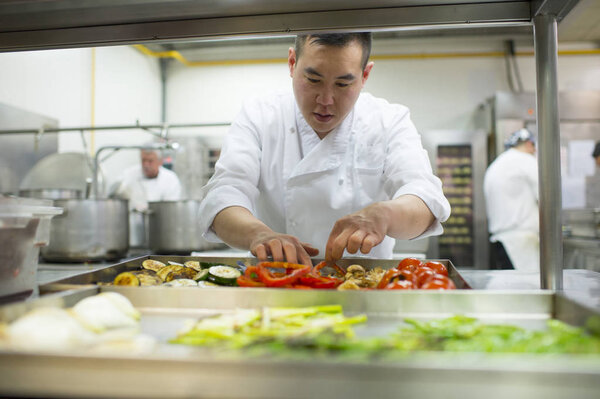 Chinese cook placing vegetables