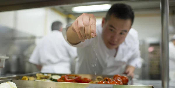 Cozinheiro chinês adicionando sal aos vegetais — Fotografia de Stock