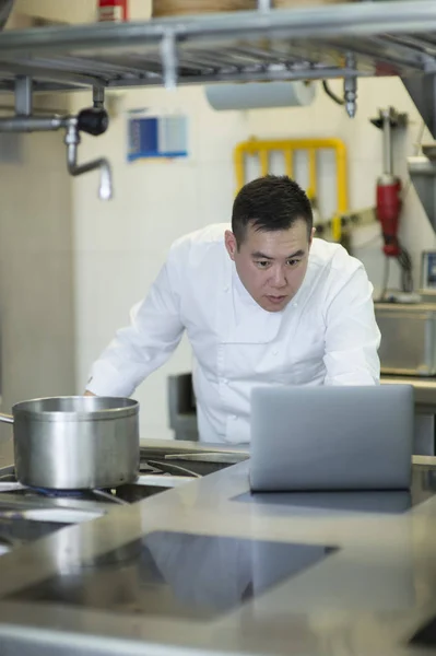 Cozinheiro chinês com computador portátil — Fotografia de Stock