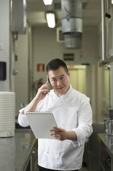 Cozinheiro chinês fala com smartphone e notebook — Fotografia de Stock