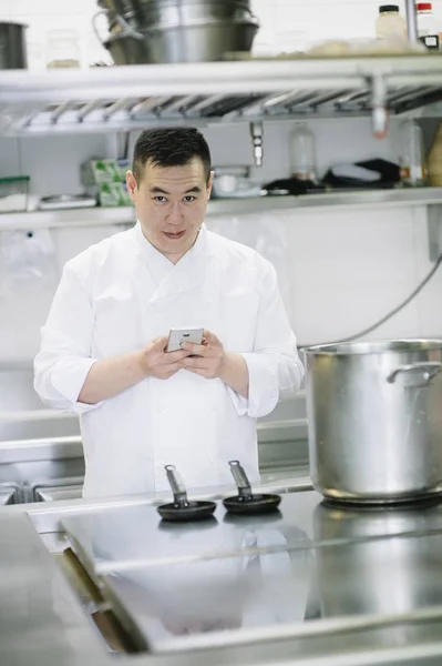 Cozinheiro chinês fala com smartphone e notebook — Fotografia de Stock