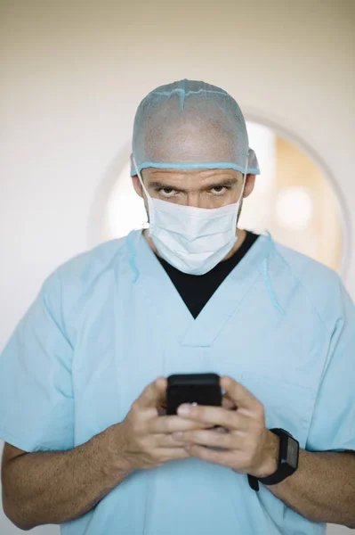 Доктор держит смартфон в коридоре — стоковое фото