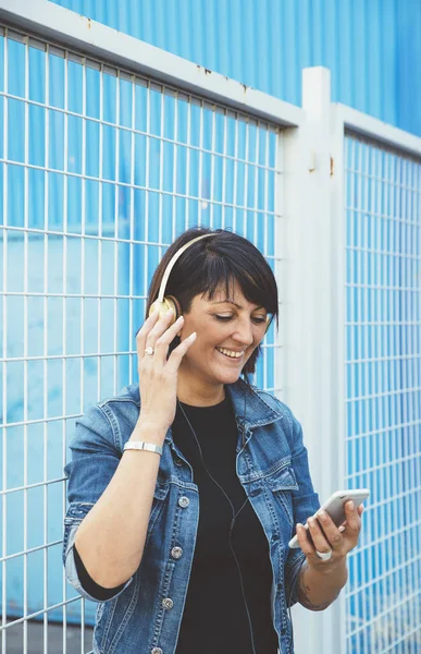Sokakta smartphone ve kulaklık ile esmer kız — Stok fotoğraf
