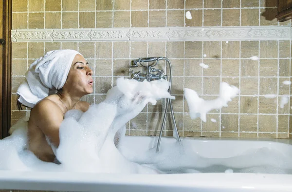 Küvette köpükle oynayan mutlu genç bir kadının portresi