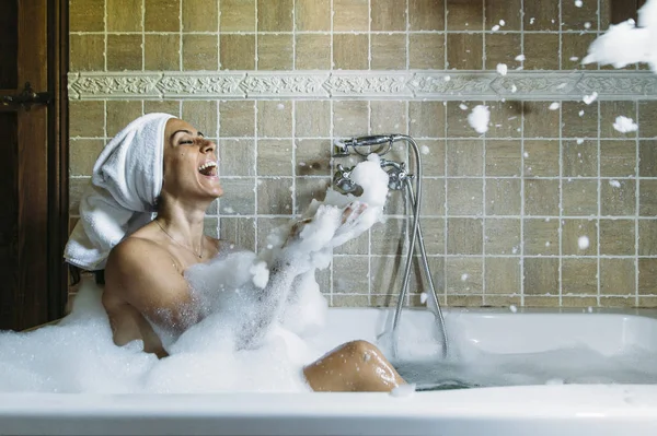 Küvette köpükle oynayan mutlu genç bir kadının portresi