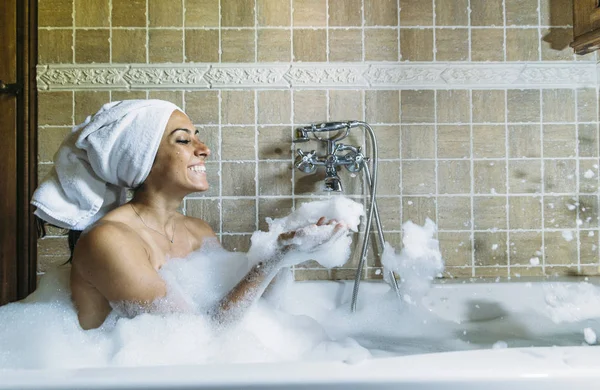 Retrato de jovem feliz brincando com espuma na banheira — Fotografia de Stock