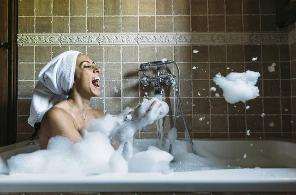 Porträtt av glad ung kvinna leker med skum i badkaret — Stockfoto
