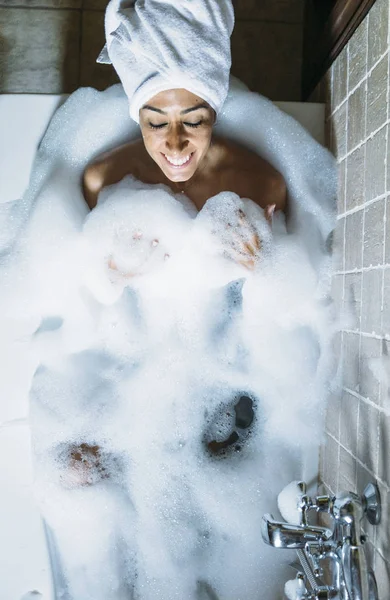 Küvette köpükle oynayan mutlu genç bir kadının portresi