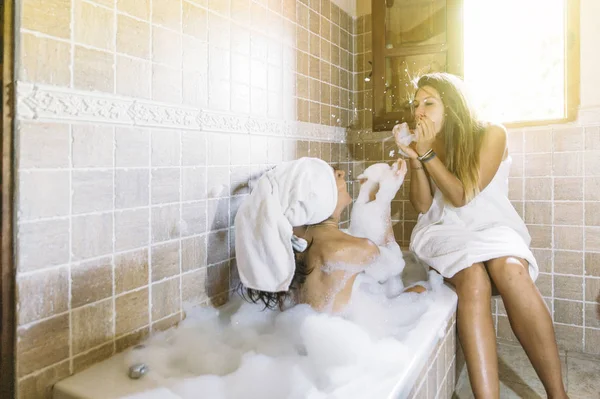 Дві щасливі лесбіянки у ванній, граючи з піною — стокове фото