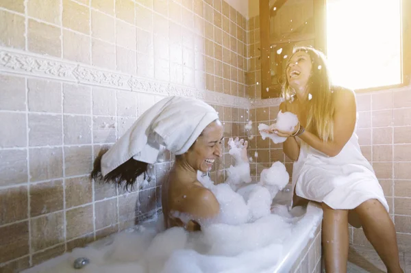 Dos lesbianas felices en el baño jugando con espuma —  Fotos de Stock