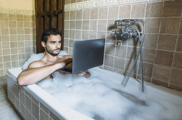Chico desnudo en cuarto de baño con portátil —  Fotos de Stock