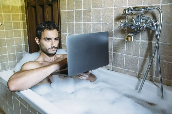 Nøgen fyr i badeværelse med laptop - Stock-foto