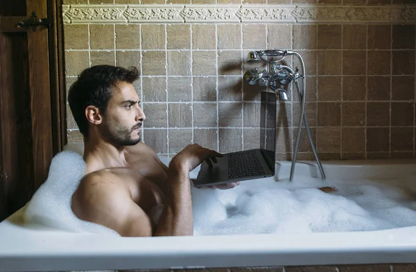 Naakte man in de badkamer met laptop — Stockfoto