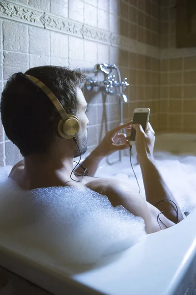 Nudo ragazzo in bagno con smartphone e cuffie — Foto Stock