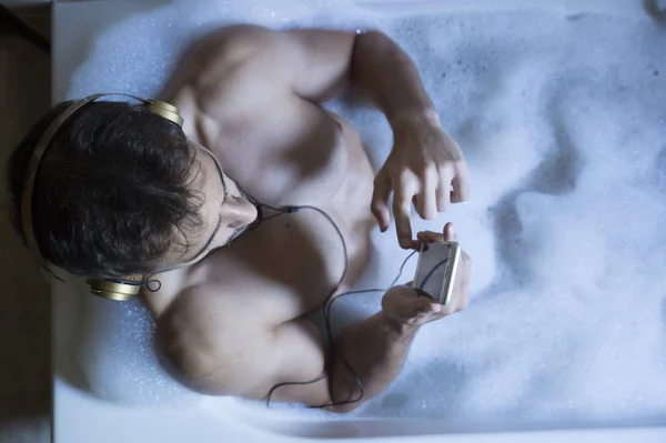 Γυμνό άντρα στο μπάνιο με το smartphone και ακουστικά — Φωτογραφία Αρχείου
