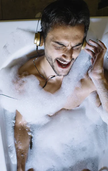 Naken kille i badrum med smartphone och hörlurar — Stockfoto