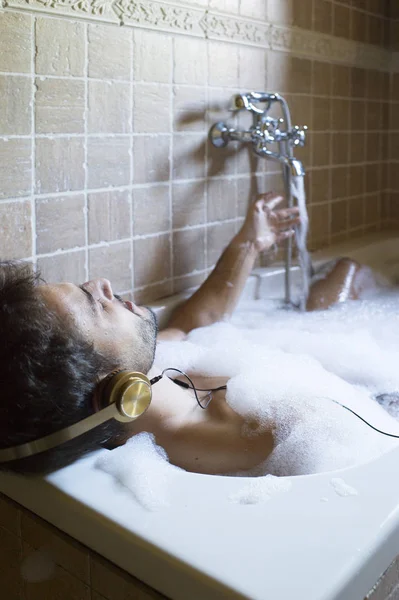 Naakte man in de badkamer met smartphone en hoofdtelefoons — Stockfoto