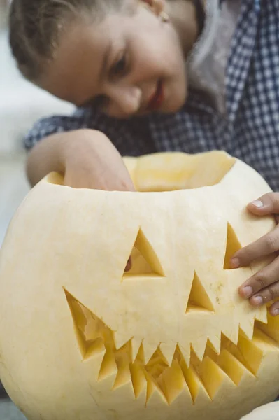 Menina esculpindo abóbora Halloween ao ar livre . — Fotografia de Stock