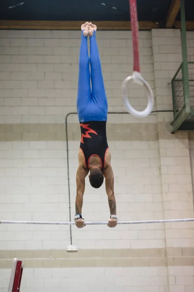 Чоловіча гімнастка виступає на гімнастичних кільцях — стокове фото
